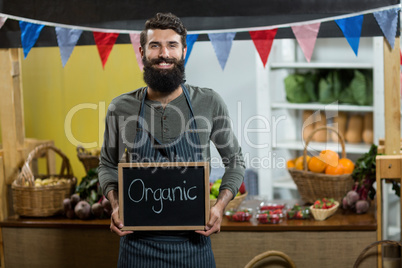 Worker holding a board with organic sign at grocery store