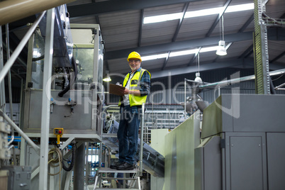 Male factory worker maintaining record on clipboard Male factory worker maintaining record on clipboard