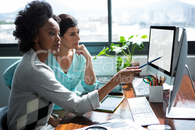 Female graphic designer pointing to desktop pc