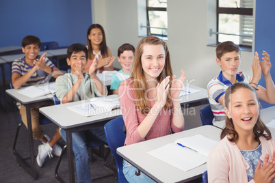 Schoolgirl clapping hands in classroom at school