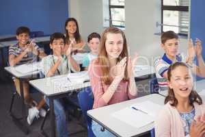 Schoolgirl clapping hands in classroom at school