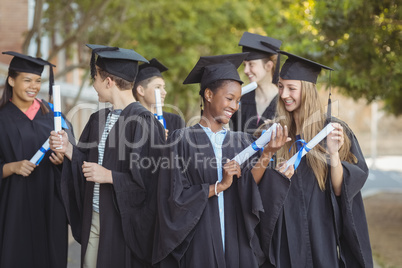 Graduate school kids standing with degree scroll in campus at school