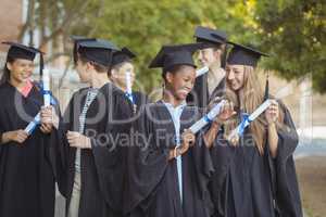 Graduate school kids standing with degree scroll in campus at school