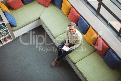 Overhead view of school teacher using digital tablet in library