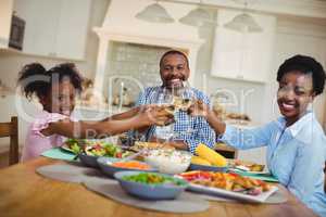 Family toasting glasses of wine and juice on dining table