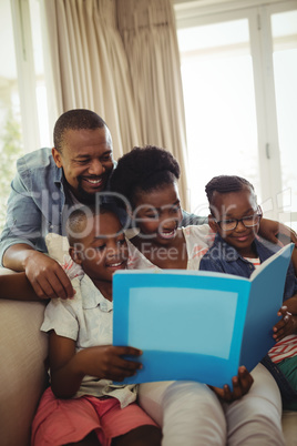 Parents and kids sitting together on sofa with photo album