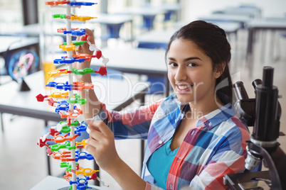 Portrait of happy schoolgirl experimenting molecule model in laboratory