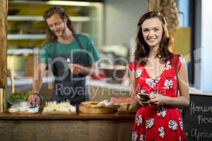 Portrait of smiling woman using mobile phone at counter