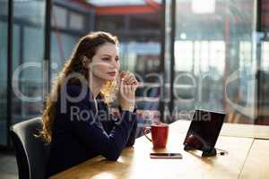 Thoughtful business executives sitting with digital tablet and cup of coffee on table