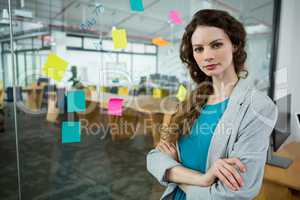 Confident female executive standing with arms crossed in creative office