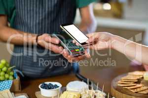 Mid section of woman paying through nfc technology at counter