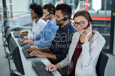 Business executives with headsets using computers at desk in office