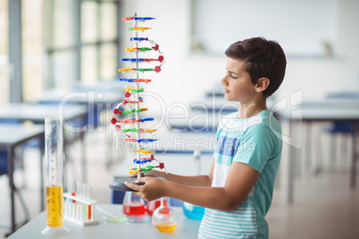 Attentive schoolboy experimenting molecule model in laboratory