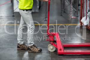 Factory worker pulling trolley in factory