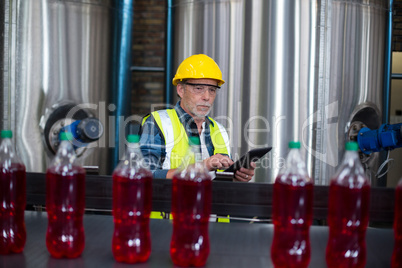 Male factory worker monitoring cold drink bottles