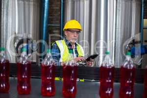Male factory worker monitoring cold drink bottles