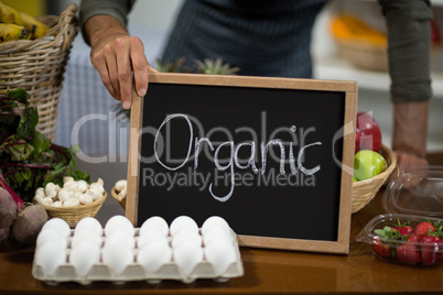 Worker holding a board with organic sign at grocery store