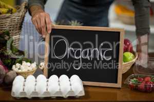Worker holding a board with organic sign at grocery store
