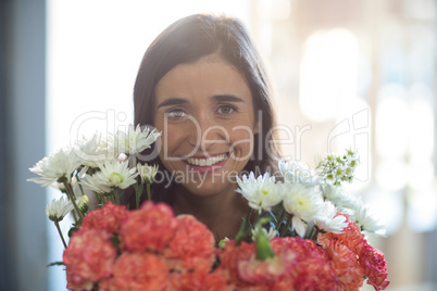 Smiling woman holding a bouquet with eyes closed in the florist shop