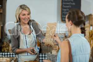 Female customer receiving a parcel from bakery staff at counter