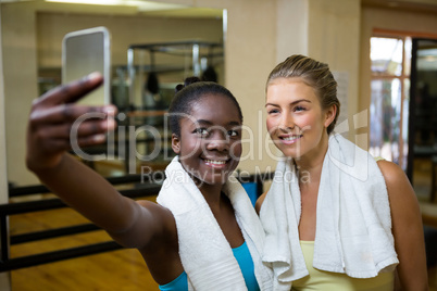 Beautiful fit women taking selfie on mobile phone after workout