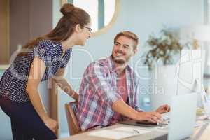 Graphic designers interacting while working on personal computer