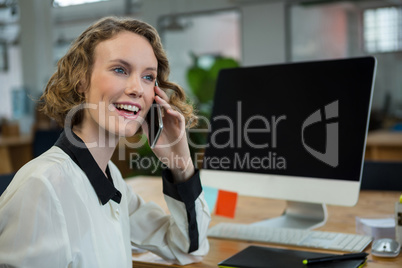 Woman sitting at desk and talking on mobile phone