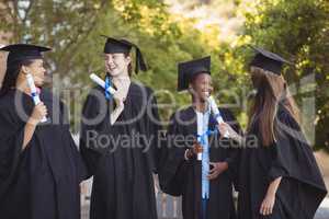 Graduate school kids standing with degree scroll in campus at school