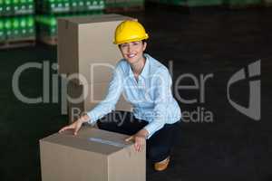 Portrait of female factory worker picking up cardboard boxes