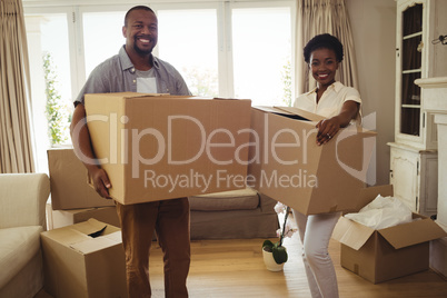 Portrait of smiling couple holding card boxes in living room