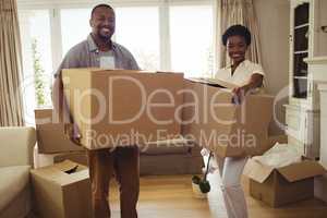 Portrait of smiling couple holding card boxes in living room