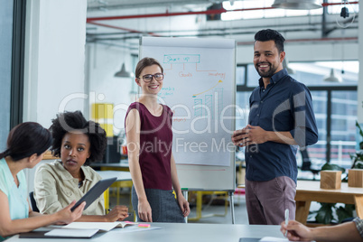 Business executives discussing over flip chart during meeting