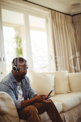 Man listening to music on mobile phone in living room