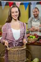 Smiling woman holding a basket at the counter in the grocery store