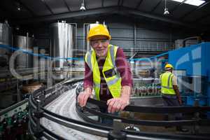 Smiling factory worker leaning on production line