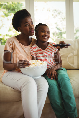 Mother and daughter watching television in living room