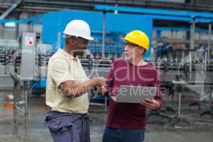 Factory workers with laptop shaking hands with his colleague