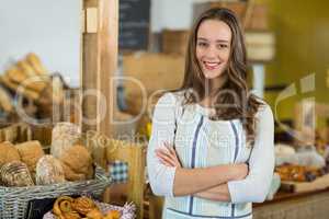 Portrait of smiling female staff standing with arms crossed at counter