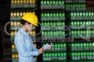 Female factory worker writing on clipboard in factory