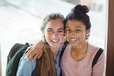 Portrait of schoolgirls embracing each other in corridor