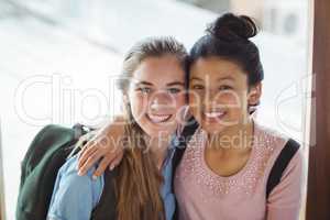 Portrait of schoolgirls embracing each other in corridor