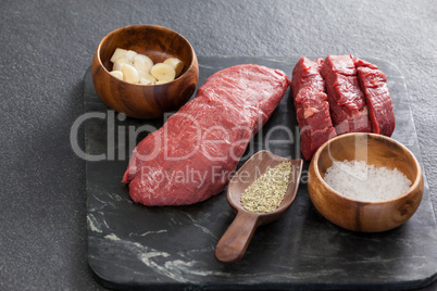 Beef steak, salt and spices on black slate plate