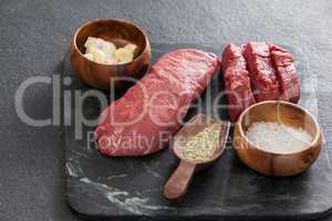 Beef steak, salt and spices on black slate plate