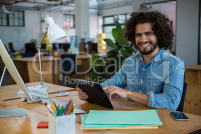 Smiling graphic designer using digital tablet in creative office