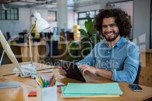 Smiling graphic designer using digital tablet in creative office