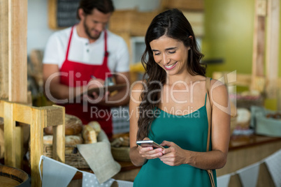 Smiling woman using mobile phone at counter