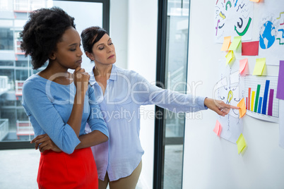 Female graphic designer pointing to the sticky notes on white board