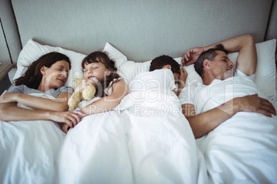 Parents and kids sleeping on bed