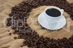 Coffee cup with coffee beans arranged on sack