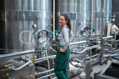 Female factory worker standing near control wheel of storage tank
